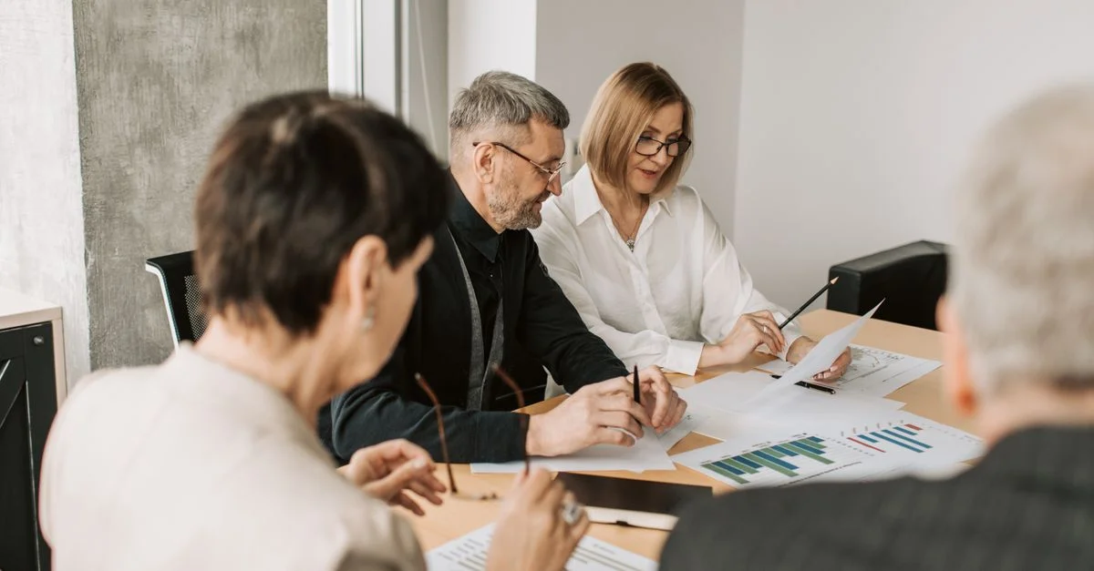 Équipe de professionnels dans un bureau analysant des documents financiers pour la stratégie commerciale.