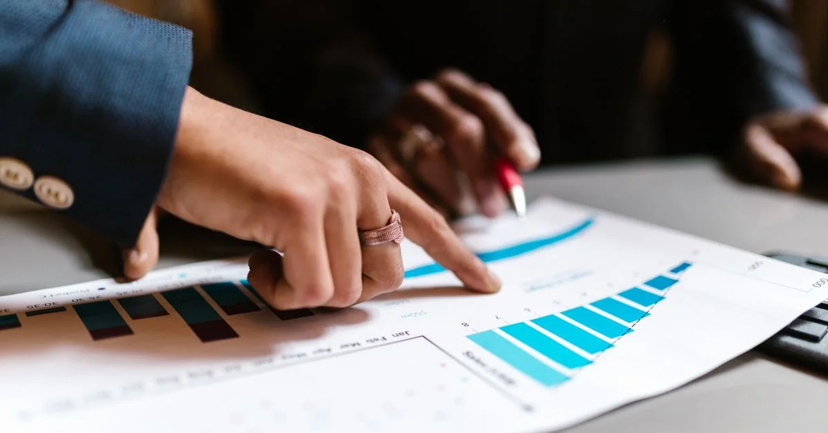 Gros plan sur des mains analysant des graphiques financiers lors d'une réunion d'affaires.