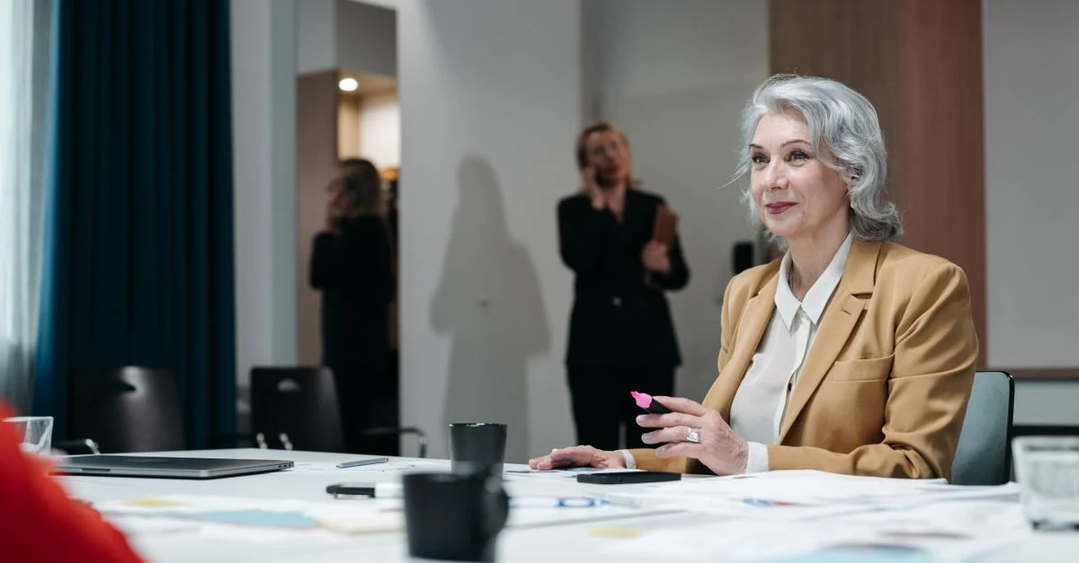 Femme d'affaires senior confiante avec des cheveux gris dans une salle de réunion, dirigeant une discussion.