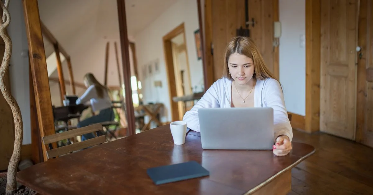 Une jeune femme utilisant un ordinateur portable à l'intérieur avec un décor en bois naturel, créant un espace de travail confortable.