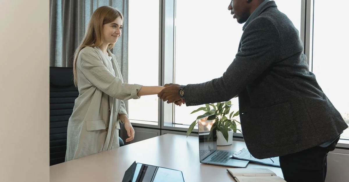 Deux professionnels du monde des affaires se serrant la main autour d'un bureau dans un bureau lumineux.