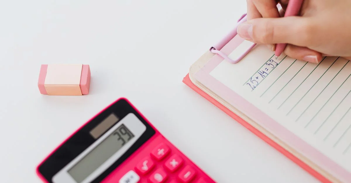 Gros plan sur des mains utilisant une calculatrice et écrivant des équations dans un carnet, parfait pour des concepts mathématiques.