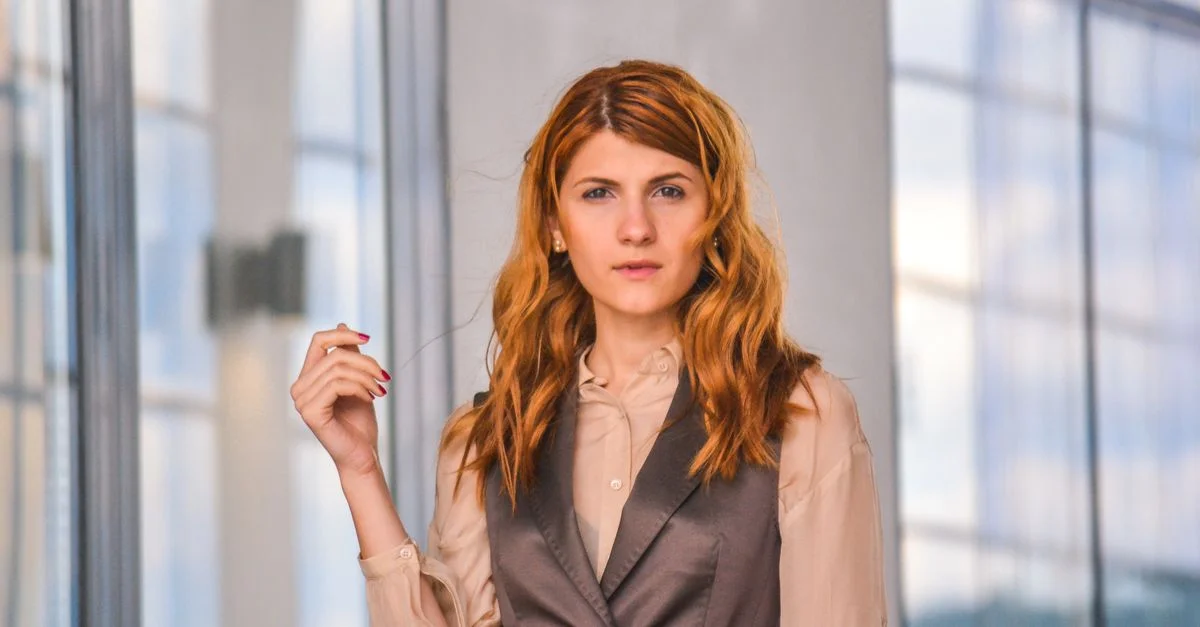 Femme confiante posant avec style à l'intérieur, entourée d'architecture moderne.
