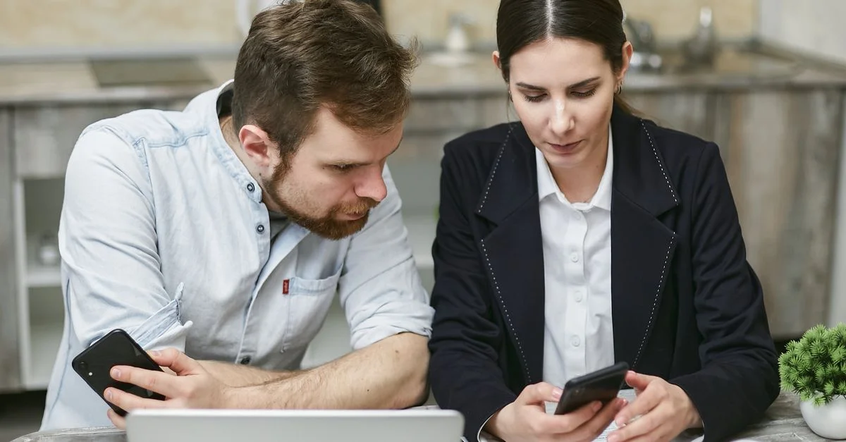 Des professionnels travaillant ensemble avec des smartphones et un ordinateur portable dans un bureau moderne.