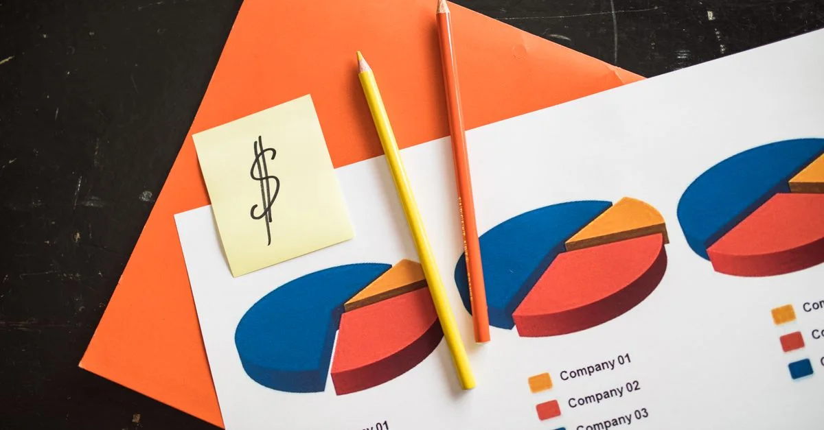 Une disposition créative de graphiques financiers en secteurs avec des crayons colorés et un billet en dollars, parfait pour des thèmes d'affaires.