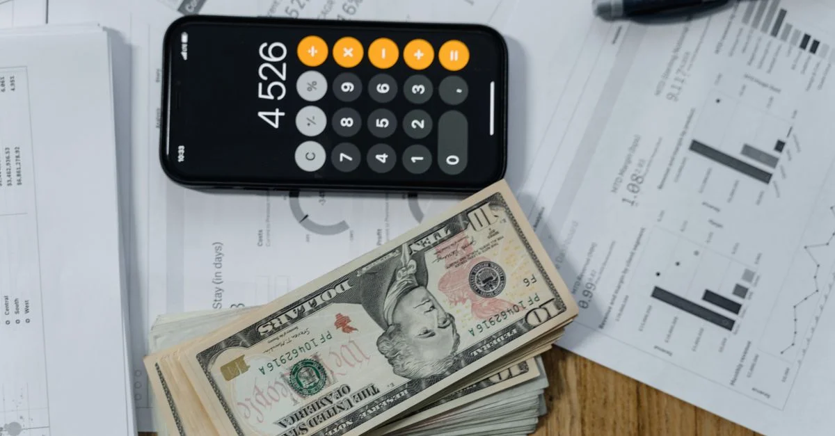 Calculatrice mobile, espèces et documents financiers sur un bureau, indiquant la planification d'affaires.